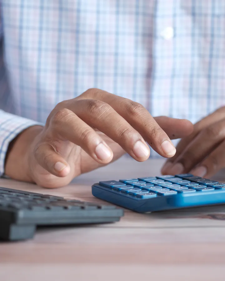 Persona calculando cifras en una calculadora sobre su escritorio